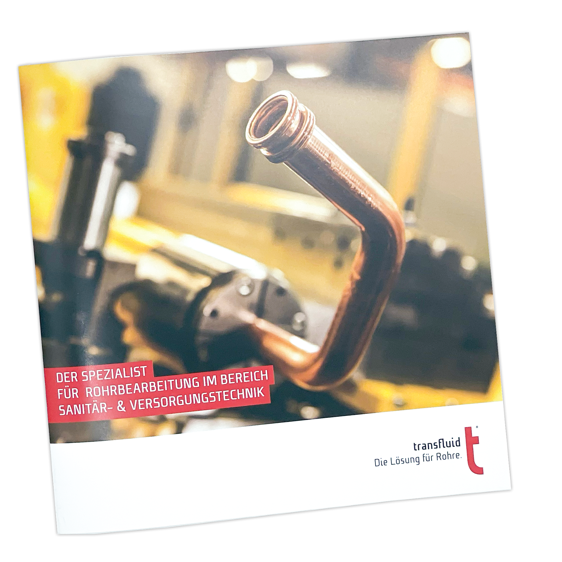 Gebogenes Kupferrohr vor industriellem Hintergrund mit transfluid Katalogdesign.