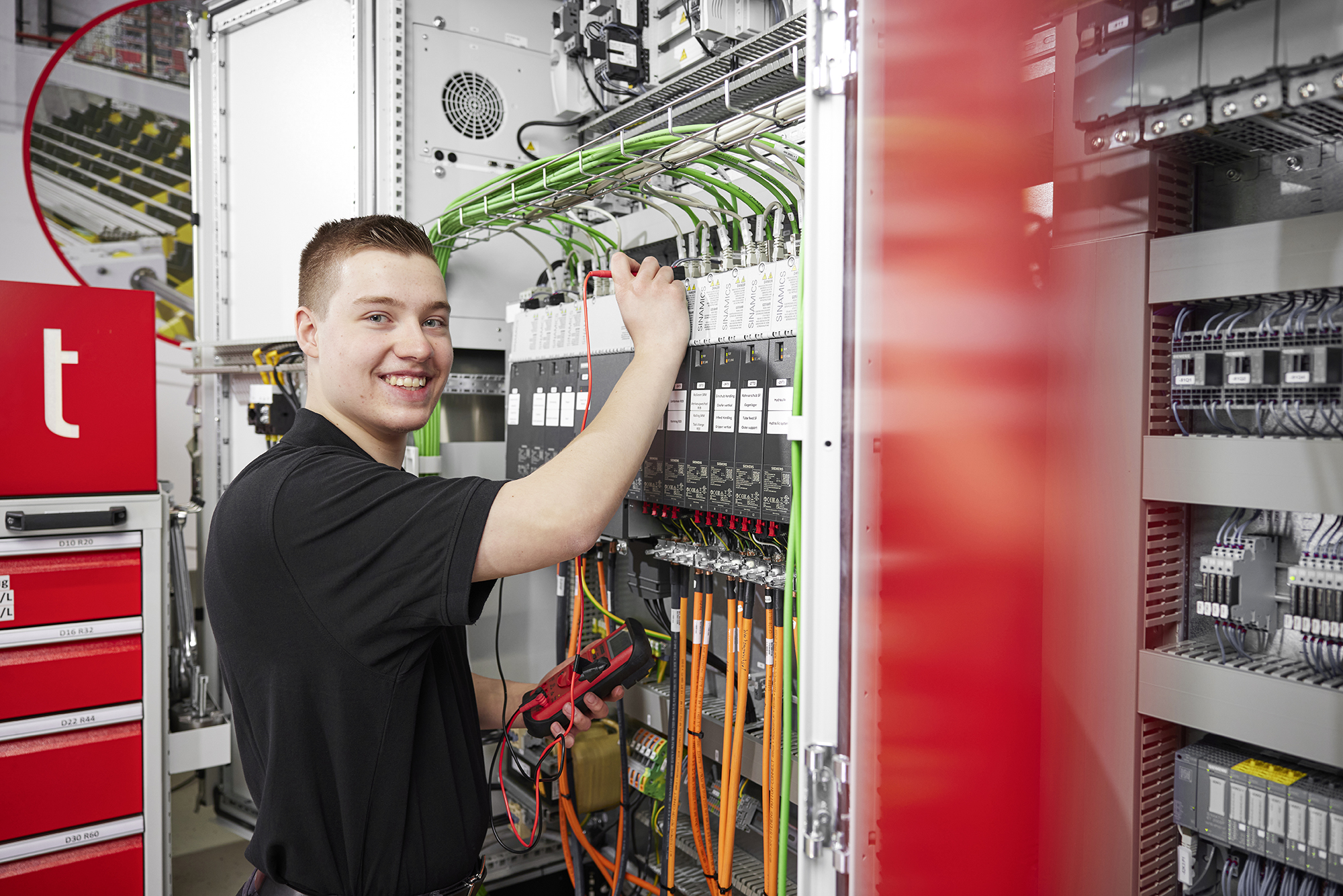 Auszubildender Elektroniker für Betriebstechnik prüft Schaltschrank bei transfluid.