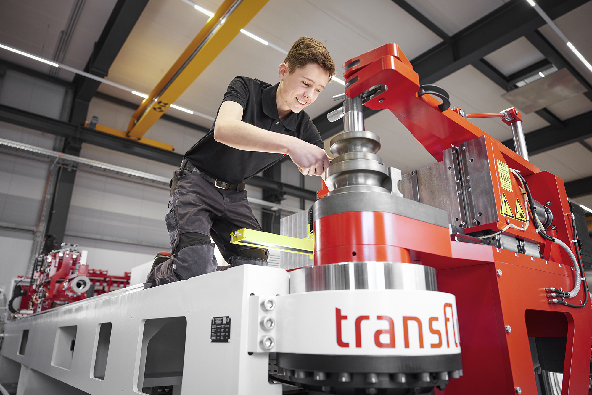 Auszubildender Industriemechaniker arbeitet an moderner Rohrbiegemaschine im Maschinenbau.