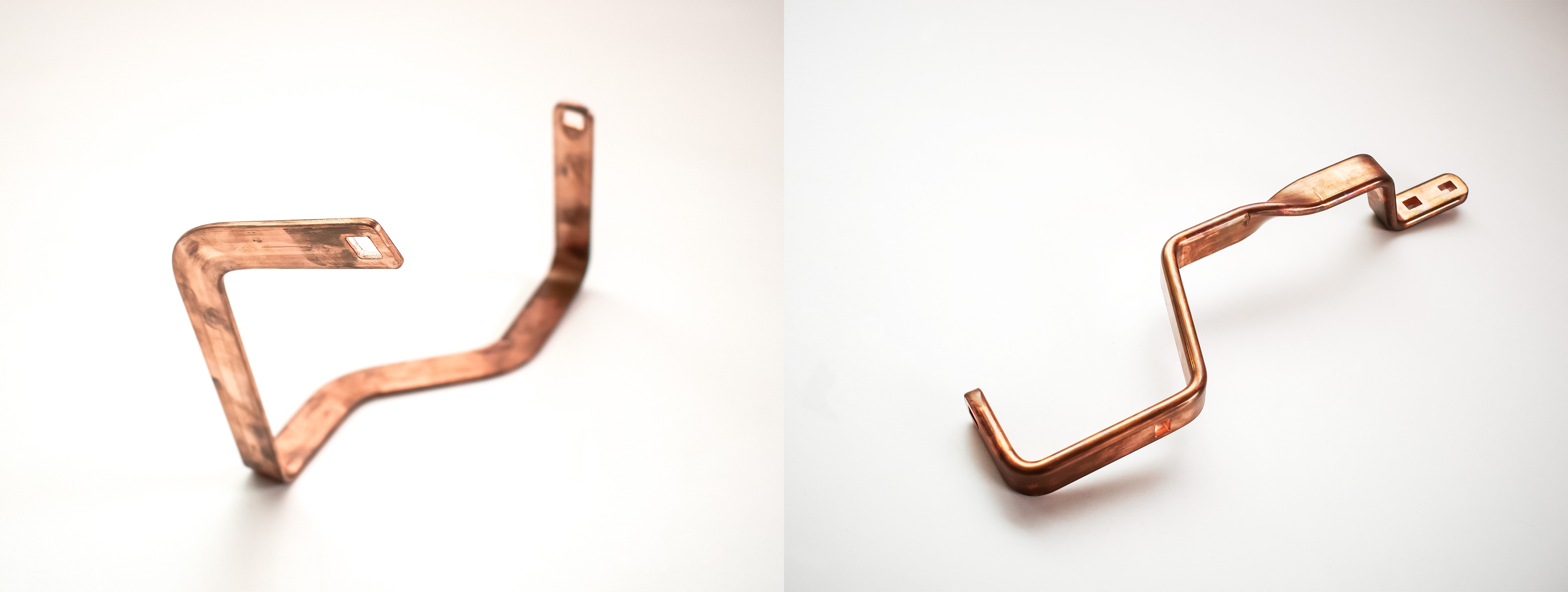 Gebogene Kupfer-Stromschienen (Busbars) für Energieverteilung auf weißem Hintergrund.