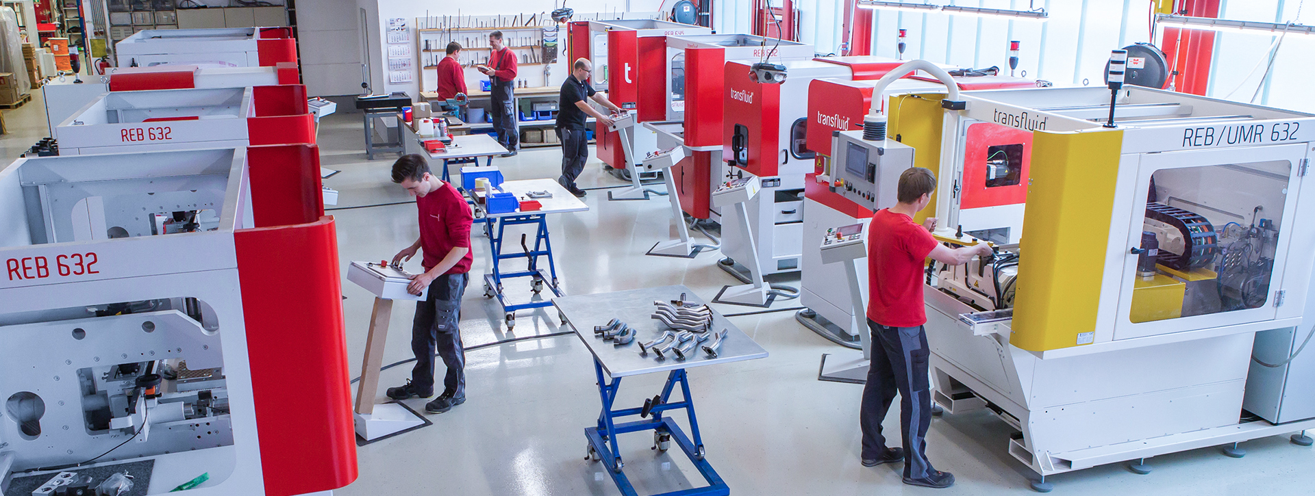 Mitarbeiter bedienen Rohrbearbeitungsmaschinen in moderner Produktionshalle.