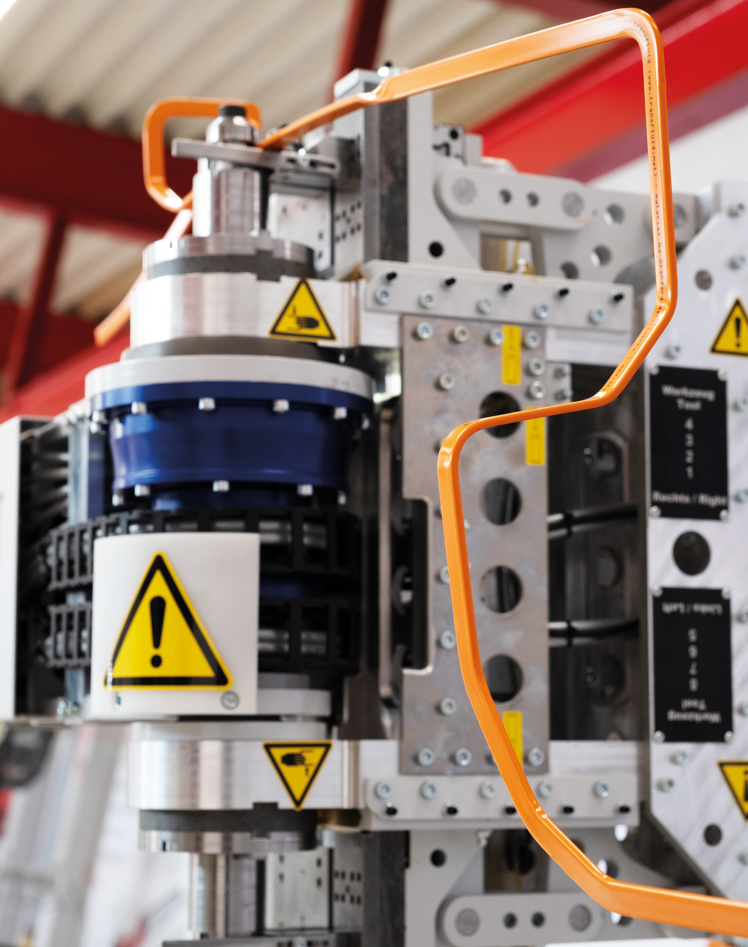 Biegekopf einer CNC-Busbar-Biegemaschine mit orangefarbener Stromschiene.