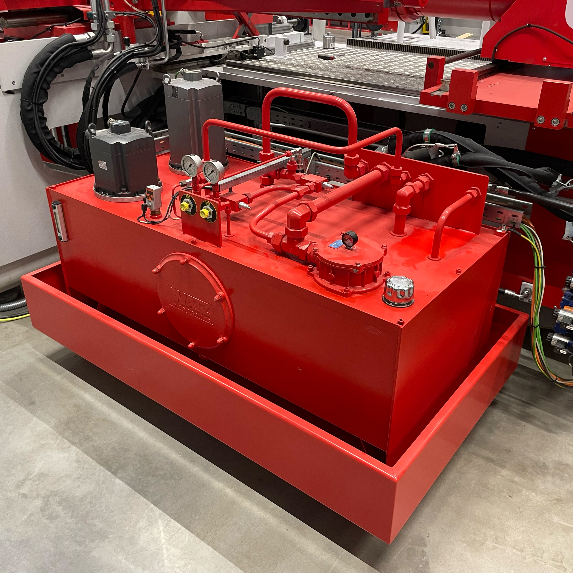 Rotes Hydraulikaggregat einer servo-hydraulischen Rohrbiegemaschine mit Servomotor, Druckanzeigen und Hydraulikleitungen zur präzisen Energieversorgung der CNC-Rohrbearbeitung.