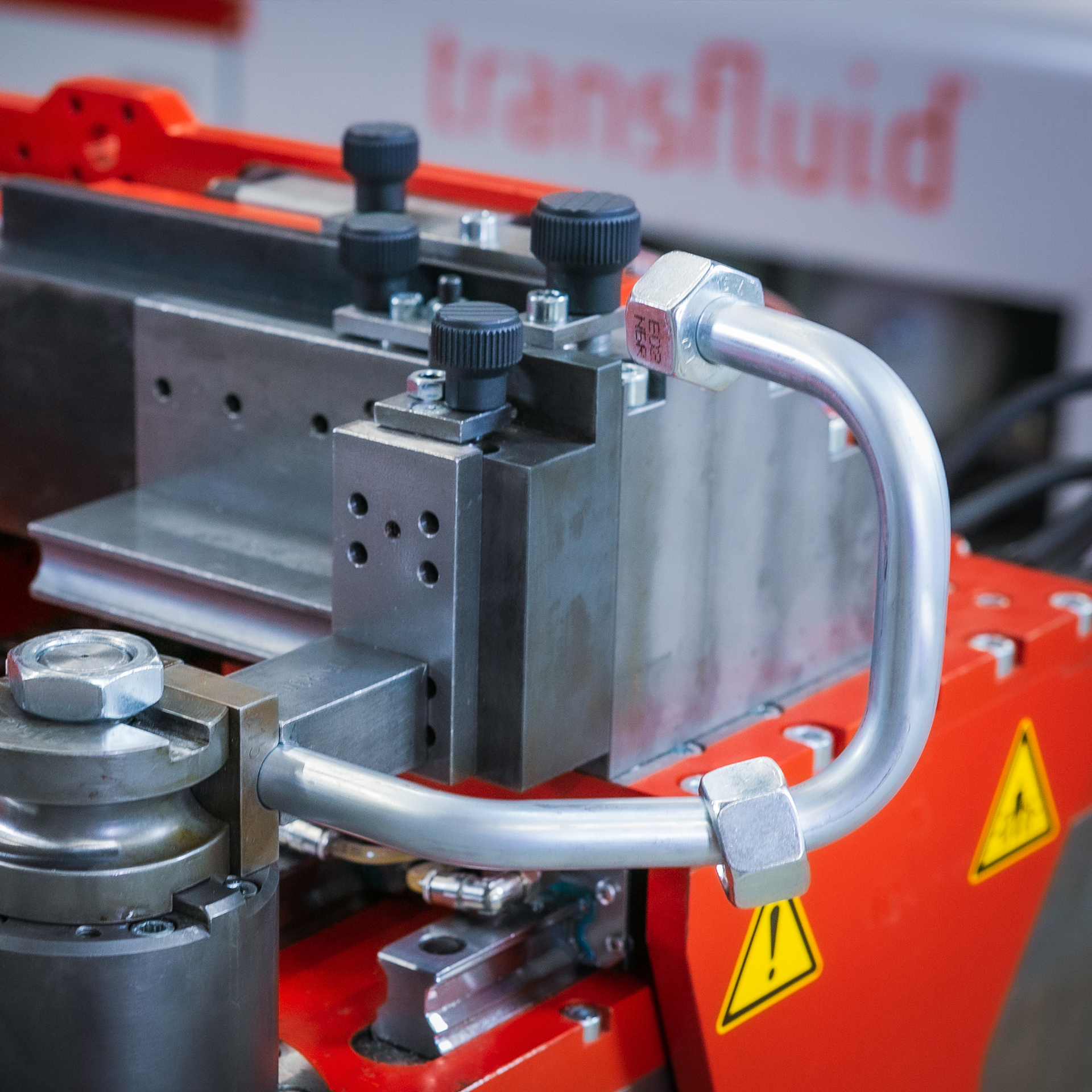 Detailaufnahme eines gebogenen Hydraulikrohrs mit Verschraubungen in einer CNC-Rohrbiegemaschine von transfluid.