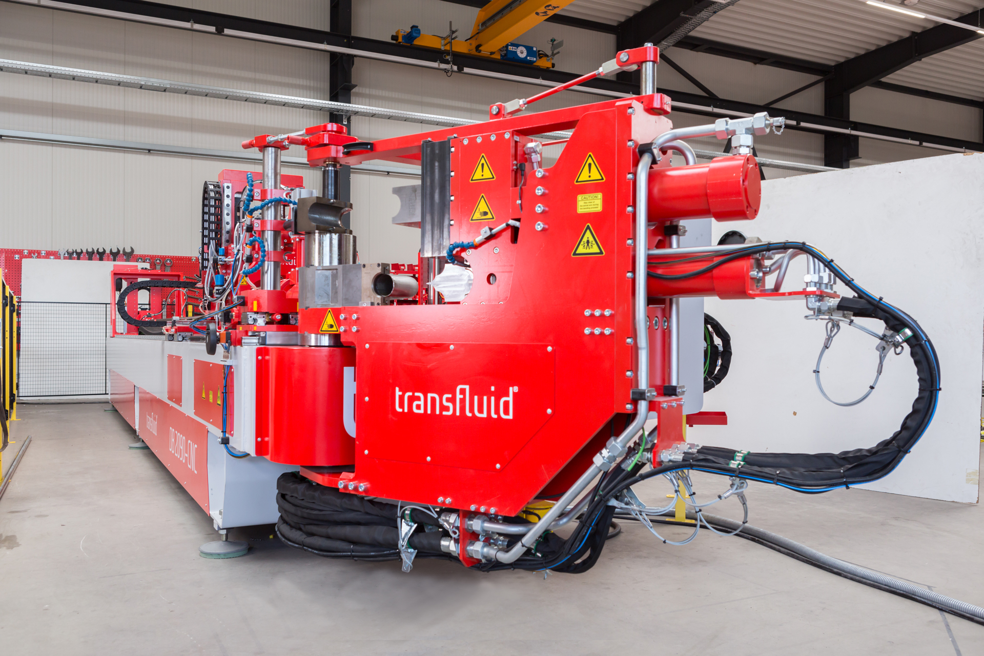 CNC-Dornbiegemaschine t bend POWERLINE 90 von transfluid in einer Produktionshalle für das präzise Biegen von Metallrohren in der industriellen Rohrbearbeitung.