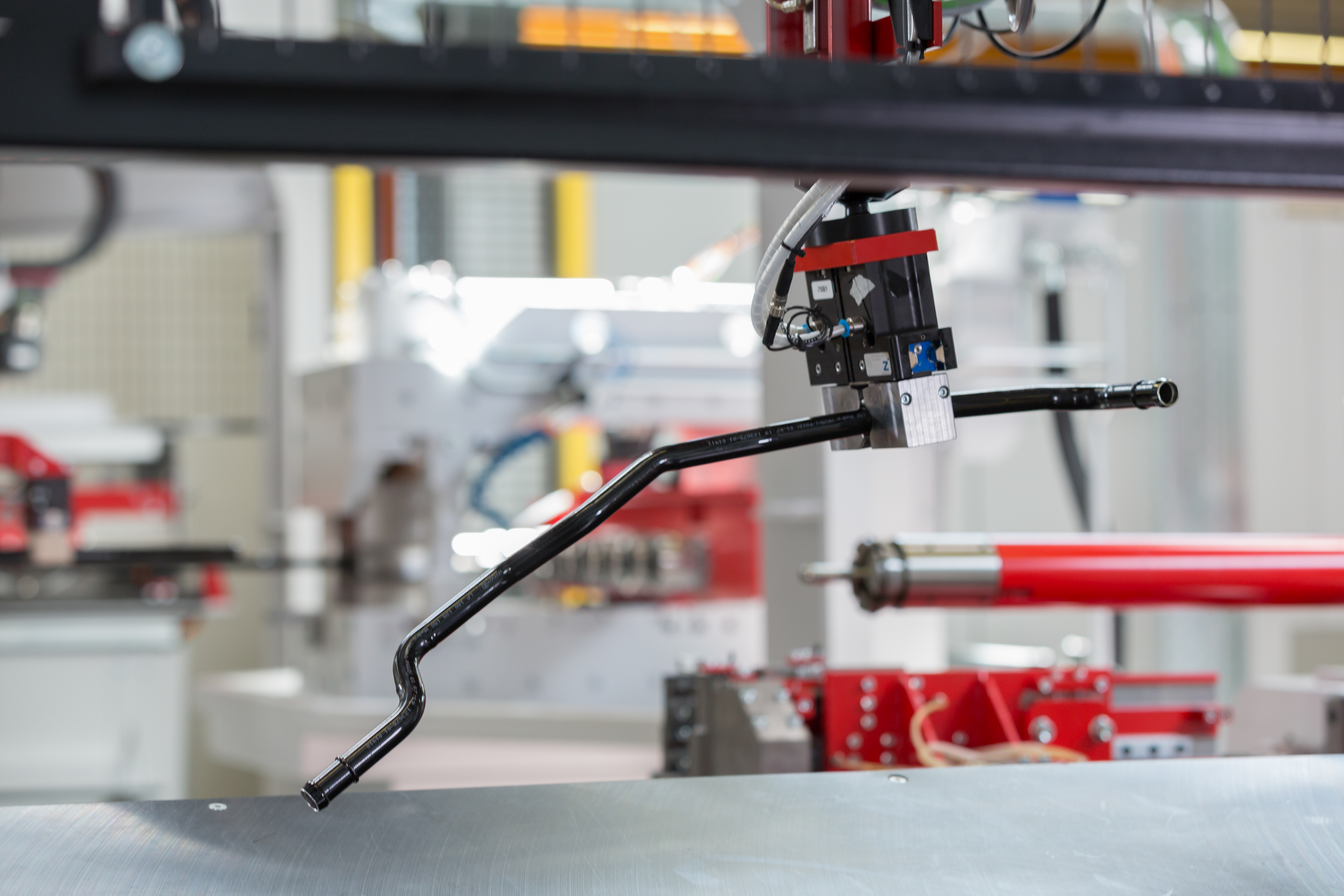 Automatisches Greifsystem einer transfluid Rohrbiegeanlage positioniert gebogenes Metallrohr in einer Produktionszelle.
