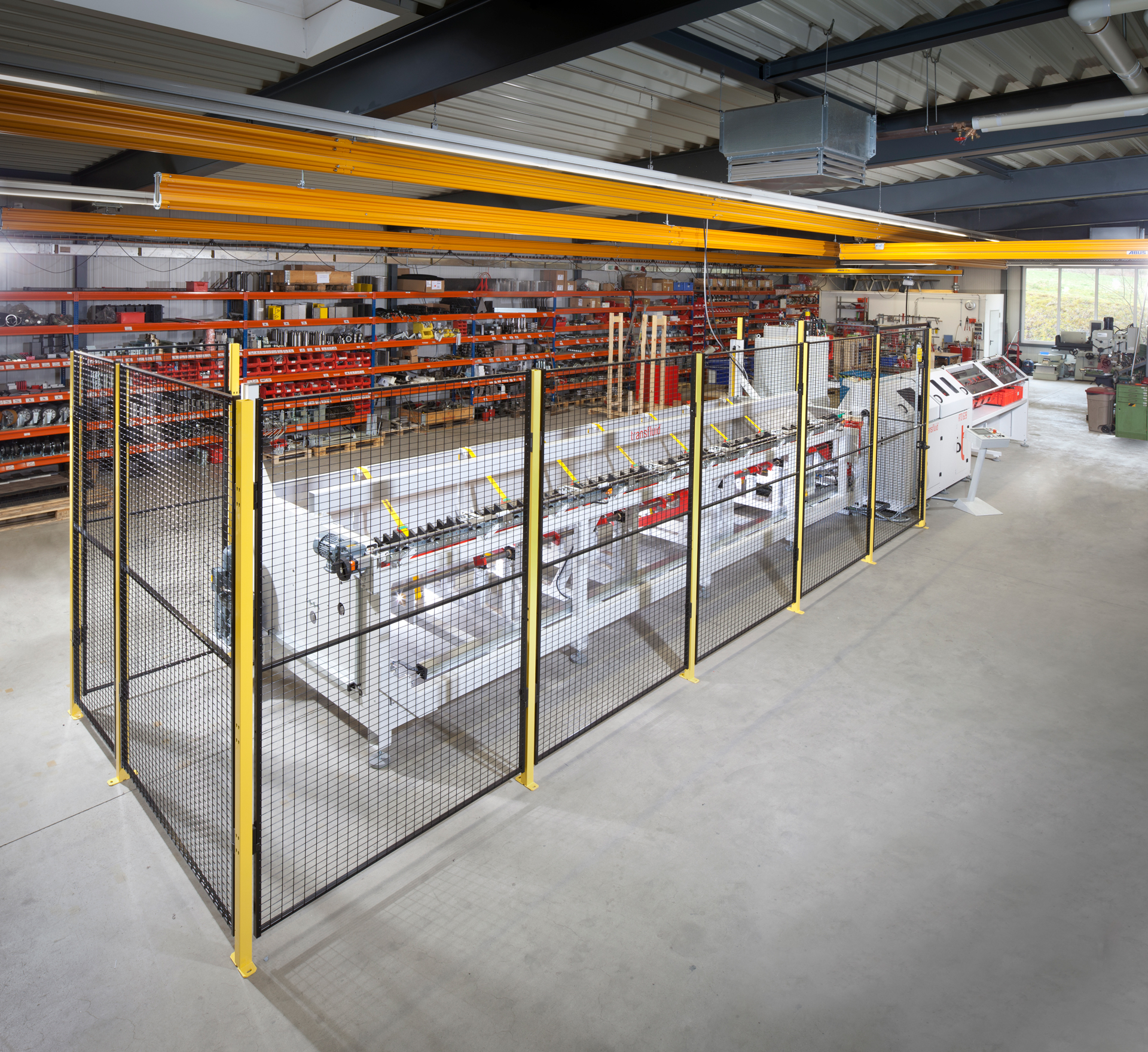 Automatisierte Rohrtrennanlage mit Schutzzaun, Rollenbahn und CNC-Steuerung für industrielle Serienfertigung von Metallrohren.