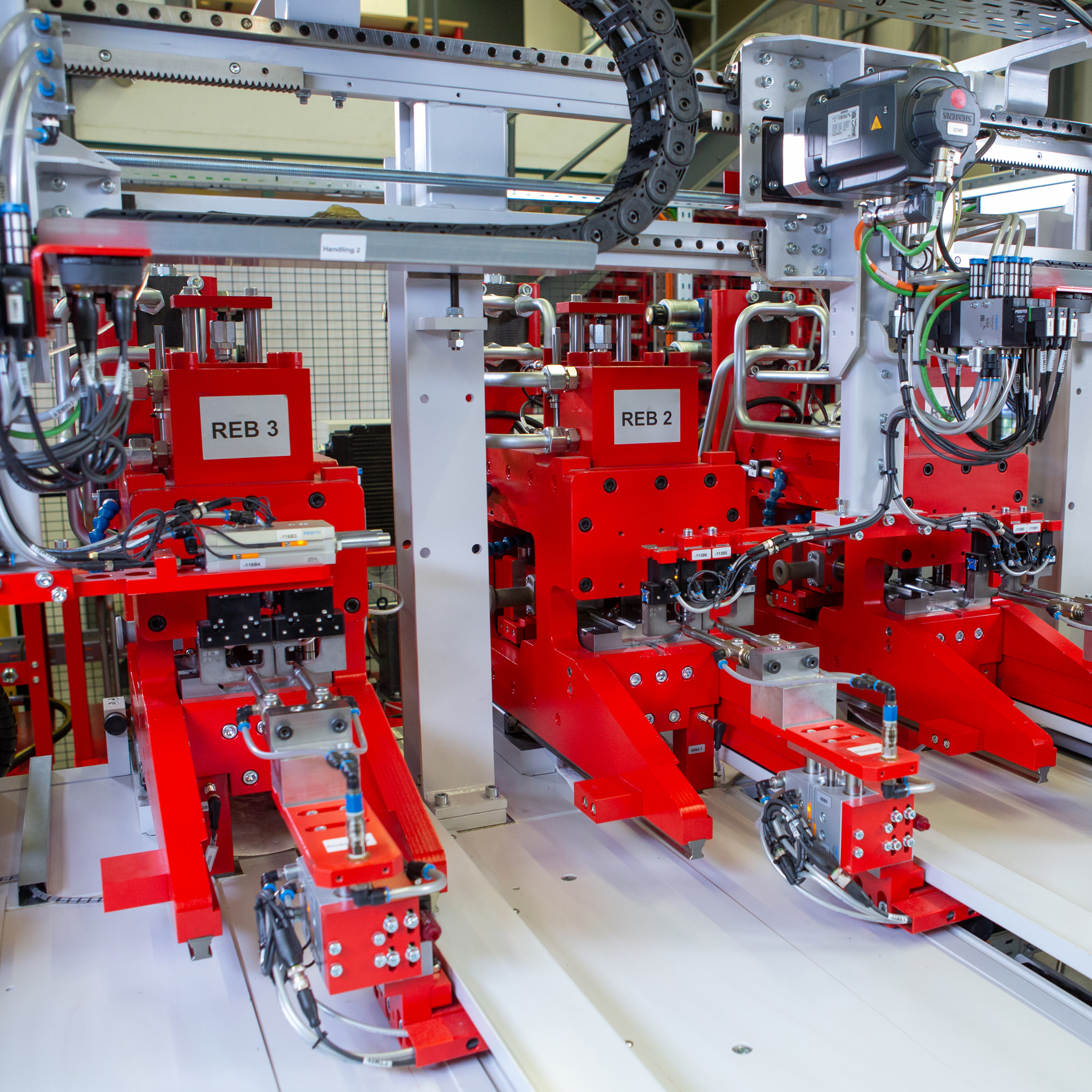 Industrielle transfluid t form BOOSTLINE Rohrumformmaschine mit mehreren roten Formeinheiten und Steuertechnik zur automatisierten Rohrendbearbeitung.