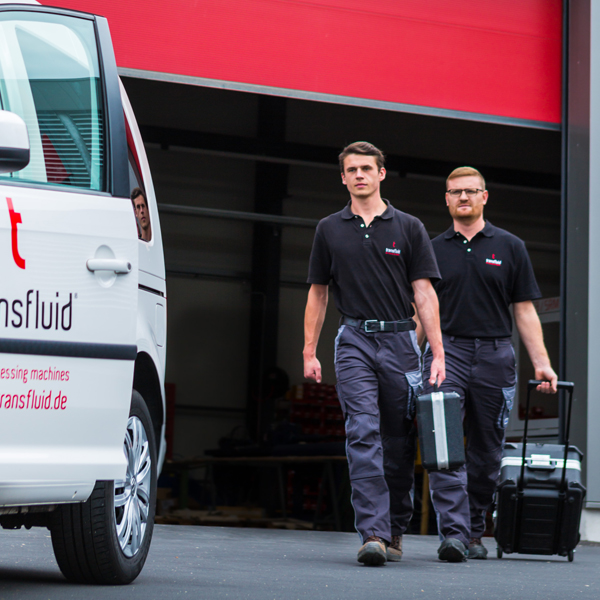 transfluid Servicetechniker mit Werkzeugkoffern vor Servicefahrzeug.