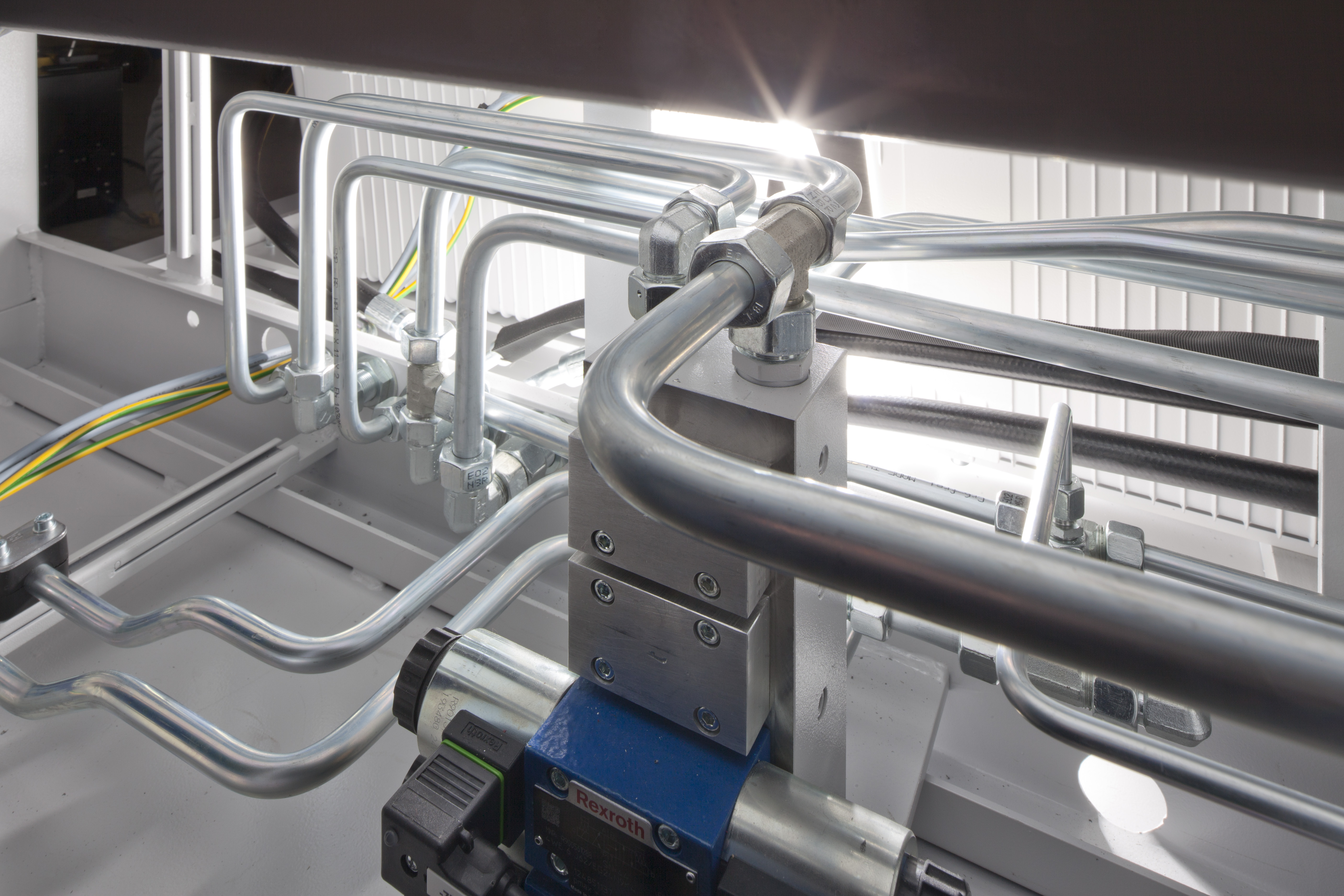 Gebogene Hydraulikrohre und Verschraubungen in industrieller Rohrverrohrung.